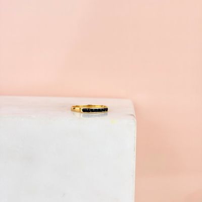 une bague en or sertie d'une pierre noire sur un bloc blanc