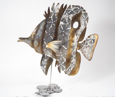 une sculpture métallique représentant un poisson, posée sur un socle