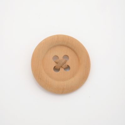 a wooden button with a cross on it on a white surface