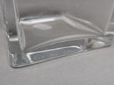a clear glass vase with a silver base on a table