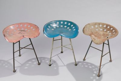 three different colored plastic stools sitting next to each other on a white surface