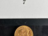 the gold coin is sitting on a black surface in front of a white box
