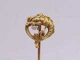 a gold brooch with a horse and a pearl in it