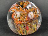 a glass paperweight with orange and white designs on it