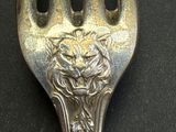 a silver fork with a lion on it on a black surface