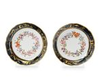 two plates with floral designs and gold rims on them