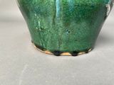 a close up of a green vase on a table