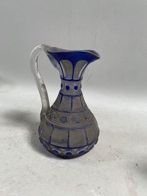 un pichet en verre bleu et blanc posé sur une table