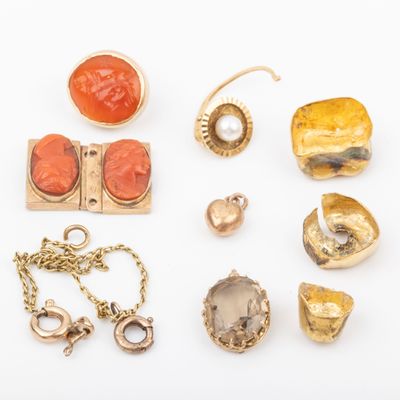 an assortment of gold and coral jewelry on a white surface