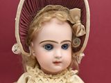 a doll that is wearing a dress and a hat