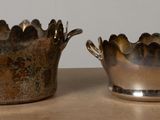 two silver vases sitting on a table next to each other