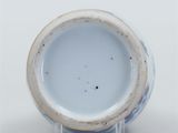 a blue and white vase with a brown rim