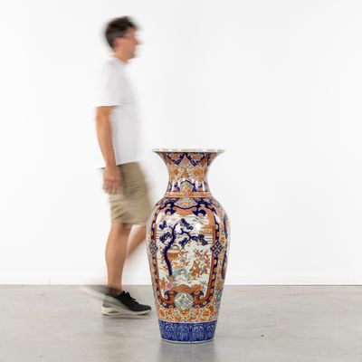 un homme passant devant un grand vase posé par terre