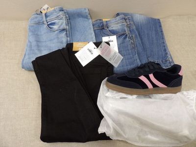 deux paires de jeans et une paire de chaussures posées sur un canapé