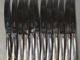 six knives and six spoons sitting on a table