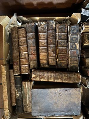 many old books stacked on top of each other in a box