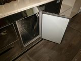 a small white refrigerator in the middle of a kitchen