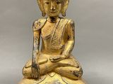 a gold statue of a buddha sitting on a wooden base