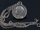 an image of a silver coin with a chain on a black surface