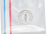 un gros plan d'une pièce de monnaie dans un sachet en plastique sur fond blanc