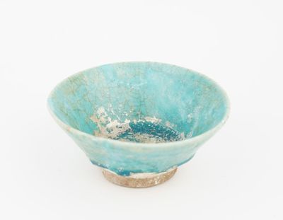 a small blue bowl with a brown rim on a white surface