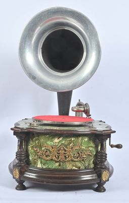 un gramophone argenté posé sur un socle recouvert d'un tissu rouge