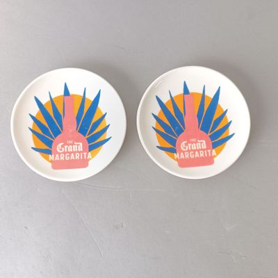 two plates with colorful designs on them sitting on a table