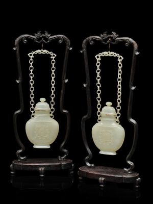 paire de vases chinois en jade sculpté, munis de chaînes et posés sur des socles