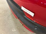 a red car with a sticker on it ' s bumper