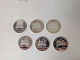 six different british coins sitting on top of a white surface