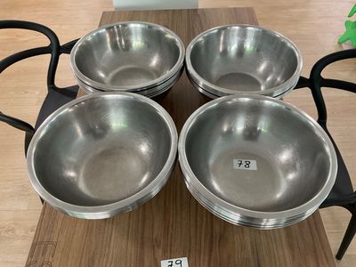 four stainless steel bowls sitting on top of a wooden table