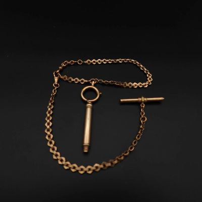 un collier en or avec une clé et une chaîne sur fond noir