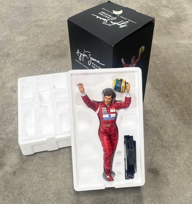 une figurine représentant un homme en combinaison de course, dans une boîte