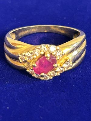 an image of a gold ring with a ruby stone surrounded by diamonds