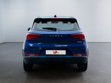 the rear end of a blue car in a room with a white wall