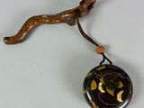 a black and gold pendant hanging from a tree branch