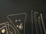 several different necklaces and earrings are displayed on a black surface