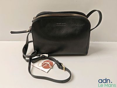 the small black purse is sitting on the table with a tag