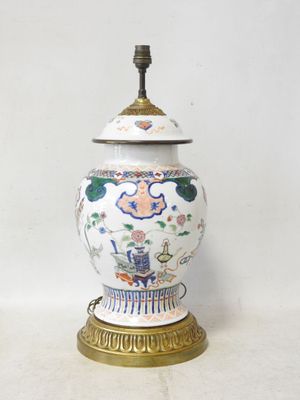 a white and blue vase with a gold base on a table