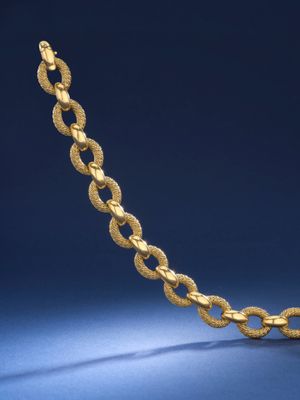 un collier en or avec un maillon torsadé sur fond bleu