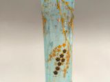 a blue glass vase with a branch of a tree on it