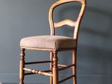 une photo d'une chaise en bois devant un mur gris