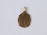 a close up of a gold plated pendant on a white surface