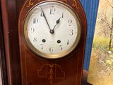 une horloge en bois posée sur une étagère à côté d'un tableau