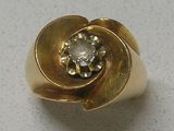 une bague en or sertie d'un diamant, posée sur une table