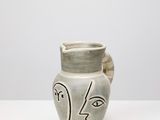 un vase orné d'un visage, posé sur une table