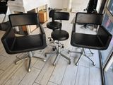 four black leather office chairs sitting in a room with a fireplace in the background