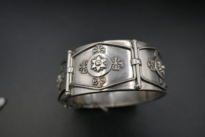 gros plan d'un bracelet en argent sur une surface noire