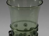 a green glass cup with a handle on a white table