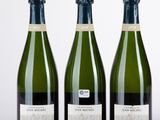 trois bouteilles de champagne sont alignées sur une surface blanche